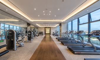There is a spacious room with multiple exercise machines and a central indoor gym area at Hainan Guest House No.2 Building