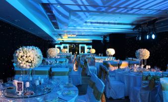 A ballroom is arranged for an event, featuring blue lighting and tables placed in the center at Jinfan Wanyuan Hotel
