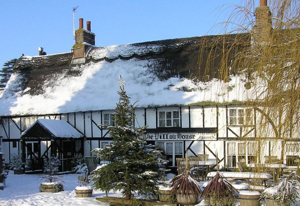 "a snow - covered building with a red roof and the name "" traveles lodge "" is displayed in the bottom right corner" at The Willow House