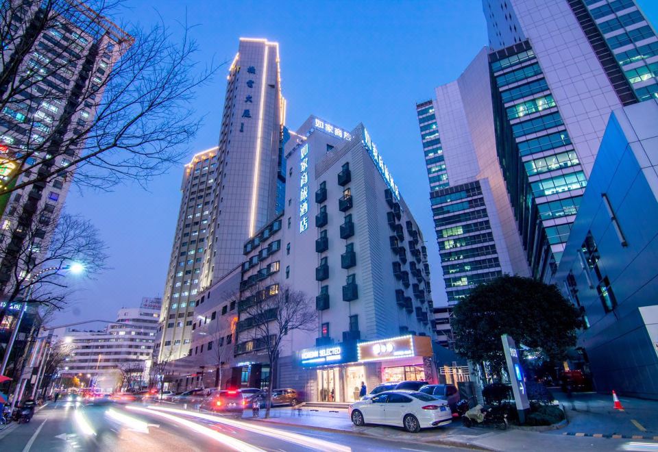 At night, a city street is lined with tall buildings and parked cars on the sidewalk at Home Inn Selected (South Square of Shanghai Railway Station)