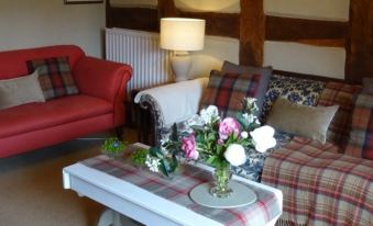 a cozy living room with a couch , a chair , and a coffee table with flowers on it at Moor Court Farm