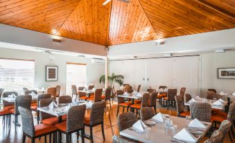 a dining room with wooden ceiling and walls , tables set for a meal , and chairs arranged around them at Scenic Hotel Bay of Islands