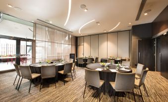 a conference room with round tables and chairs , a large window , and modern lighting at Pan Pacific Melbourne