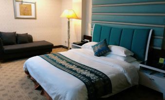 a large bed with a blue headboard and white linens is in a hotel room at Diamond Hotel