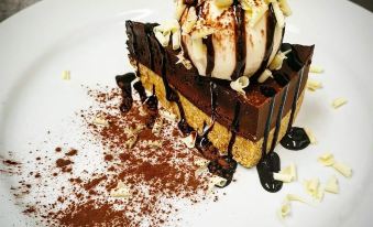 a white plate with a chocolate cake topped with ice cream and chocolate drizzle , sitting on a dining table at The Horseshoe & Castle