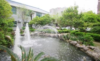 is located in front of a group of buildings, with a small pond and an artificial waterfall at Jinjiang Inn Style (Shanghai Pudong Airport Town)