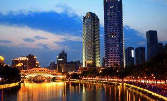 A city at night with tall buildings and skyscrapers lining the river at Howdy Smart Hotel (Chengdu Chunxi Taikoo Li)