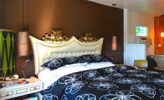 a modern bedroom with a white bed , black and white floral bedding , and gold accents at Motel Lodge