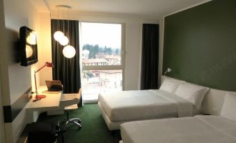 a hotel room with two beds , a desk , and a window , all decorated in white and green at Idea Hotel Milano Malpensa Airport