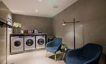 A room with washing machines and chairs is located in the laundry area, adjacent to an open doorway at Home Inn (Shanghai North Bund Dalian Road Subway Station)