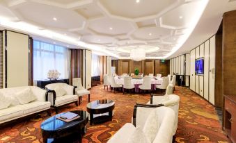 The room features tables and chairs arranged in the center, complemented by an area rug that covers the floor, providing a warm and welcoming space for guests to socialize at Ocean Hotel