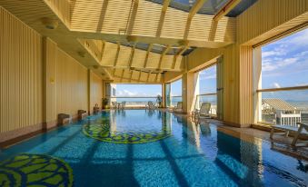 The indoor pool offers a picturesque view of the water and blue sky through its large windows on a sunny day at Rio Hotel
