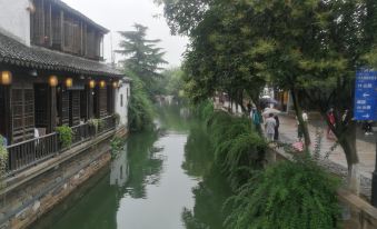 A city with people walking down the street and buildings on both sides at Yiman Hotel (Suzhou Pingjiang Road Scenic Area)