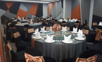 a large banquet hall filled with round tables and chairs , ready for a formal event at Hotel Fuse Rayong