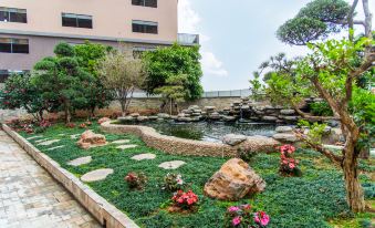 There is a small pond in the middle, surrounded by rocks and plants, located next to an artificial structure at Lavande Hotel