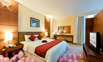 a large bed with a red blanket and pillows is surrounded by pink balloons in the room at Muong Thanh Dien Chau Hotel