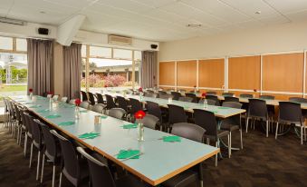 a conference room with multiple rows of tables and chairs arranged for a meeting or event at Garden Hotel