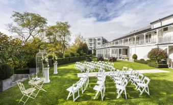 a large white wedding ceremony is taking place in a grassy area with rows of chairs set up for guests at Hilton Lake Taupo