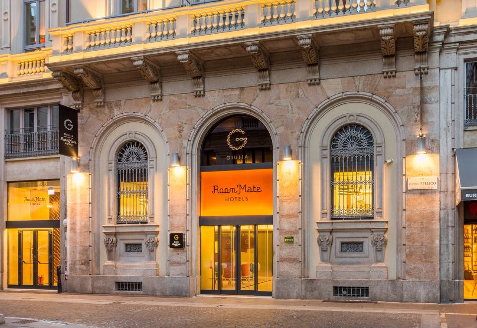 a large building with an orange sign above the entrance , creating a welcoming atmosphere for guests at Room Mate Giulia