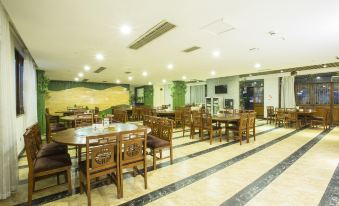 a large dining room with wooden tables and chairs , and a television mounted on the wall at Panda Hotel