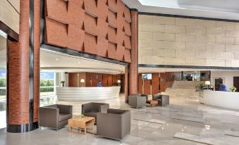 a modern hotel lobby with a large reception desk and several chairs arranged around it at Oakwood Hotel and Residence Kuala Lumpur