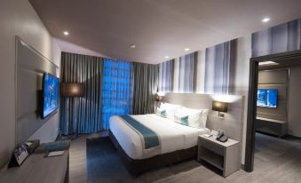 a modern hotel room with a large bed , blue and white curtains , and a flat - screen tv at bai Hotel Cebu