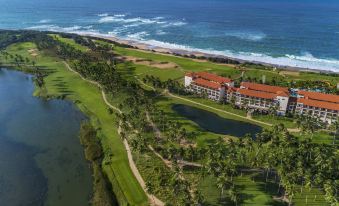 aerial view of a golf course near the ocean , featuring multiple golf carts on the course and a building in the background at Shangri-La's Hambantota Golf Resort and Spa, Sri Lanka