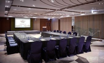 a conference room with a long table surrounded by chairs and a projector screen at the front at Dorsett Wanchai