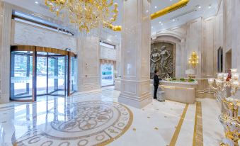 a person is standing in a lobby with a gold chandelier and white marble flooring at Vienna Hotel