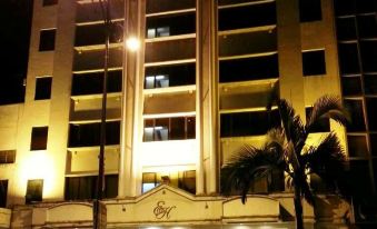 a tall building with a large entrance and palm trees in front of it at night at The Executive Hotel Lahad Datu