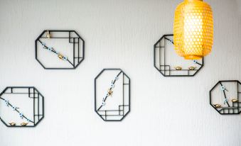 a collection of hexagonal metal framed pictures hanging on a white wall , with a yellow lamp in the center at Gengting Hotel