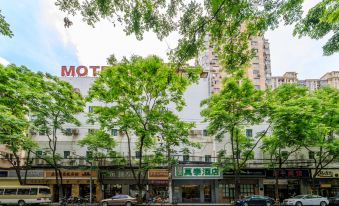 There is a street with trees and buildings on both sides, including an oriental style building at Motel Hotel (Shanghai Changping Road Metro Station)