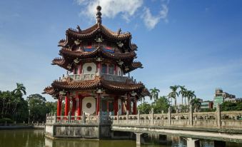 a traditional chinese pagoda with a red roof and white walls , surrounded by water and trees at Han She Business Hotel