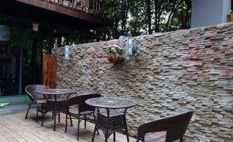 There is an outdoor patio with tables and chairs next to a stone wall that has an attached deck area at Beehome  Hostel