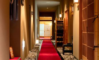 a long , red carpeted hallway with wooden doors and a staircase leading to an upper level at Ryokan Warabino