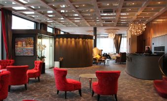 a hotel lobby with red chairs and a large reception desk , creating a welcoming atmosphere at The Ambassador