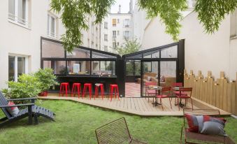 a small courtyard surrounded by buildings , with several red chairs placed around the area for outdoor dining at Hotel Izzy