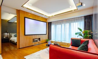 a modern living room with a large flat screen tv mounted on the wall and a red couch at The One Hotel