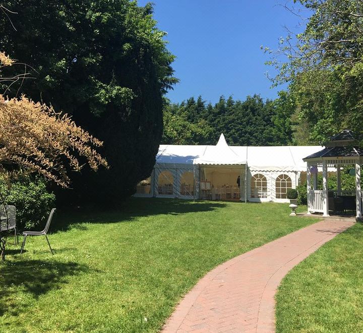 a beautiful outdoor setting with a white gazebo surrounded by lush green grass , trees , and a brick path leading to a gazebo at Blue Pigeons