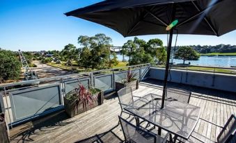 a rooftop patio with a table , chairs , and an umbrella overlooking a body of water at Cockatoo Island Accommodation