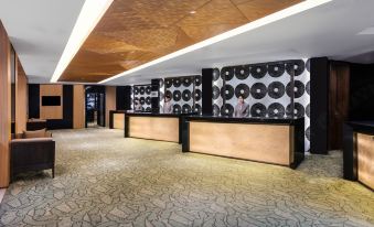 The lobby features two reception desks and a wall with an art deco design at Courtyard by Marriott Shanghai Central
