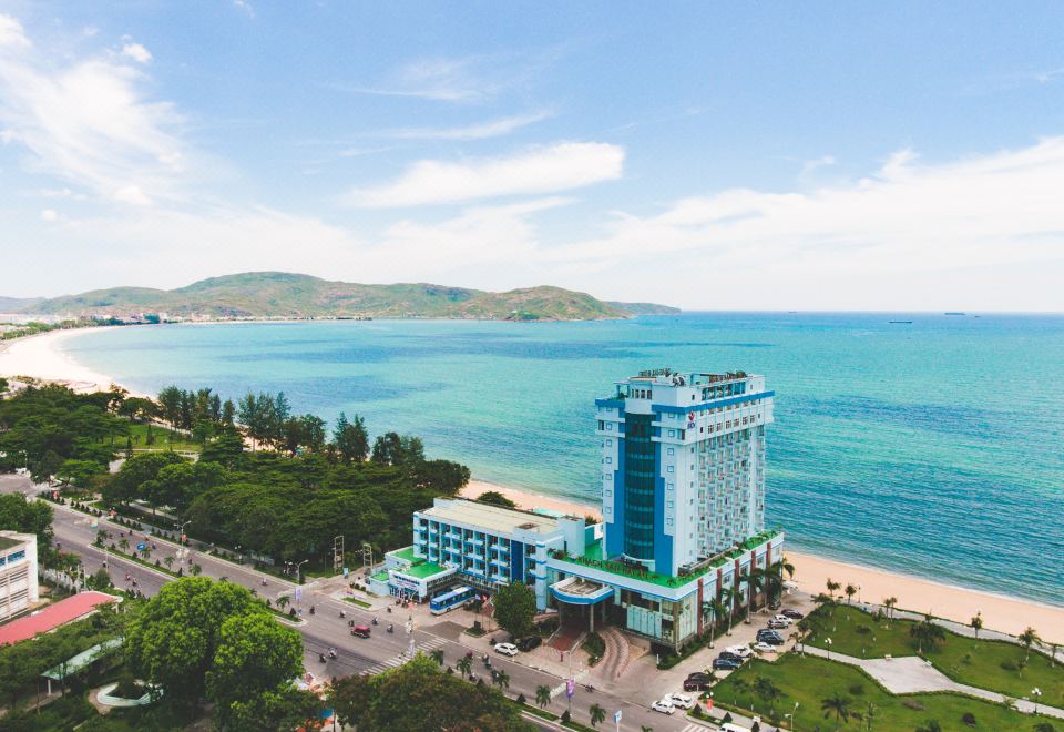 aerial view of a blue and white building on the coast , surrounded by water and trees at Seagull Hotel
