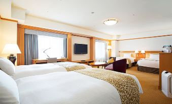 a hotel room with two beds , a desk , and a flat - screen tv . also a couch in the room at Hotel Nikko Kansai Airport
