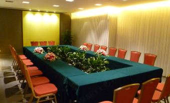 A meeting room is set up with a long table and green chairs, accommodating 10 people at Jinjiang Inn Select (Shanghai Nanjing Road Pedestrian Street)