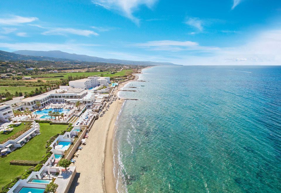 aerial view of a beautiful beach resort with multiple swimming pools , clear blue water , and lush green grass at Grecotel Lux.ME White Palace