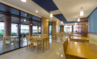 a modern , spacious restaurant with wooden tables and chairs , large windows , and a blue ceiling at Siva Royal Hotel
