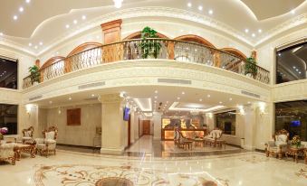 a large hotel lobby with a marble floor , white walls , and a grand staircase leading to the second floor at Riverside Hotel Quang Binh