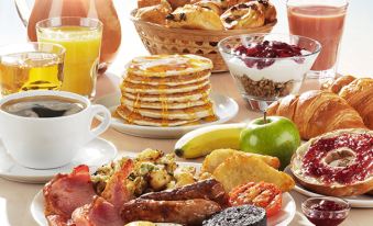 a table is filled with a variety of breakfast foods , including pancakes , fruit , toast , and cookies at Premier Inn Whitehaven