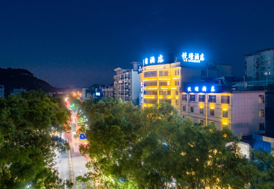 a city street at night , with a tall building illuminated and surrounded by trees and cars at GuiLin ParkView Hotel