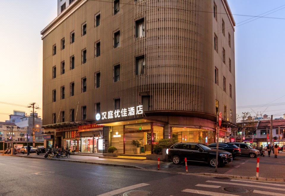 There is a street with cars and buildings on both sides, including an oriental-style building at Hanting Youjia Hotel (Shanghai East Nanjing Road Branch)